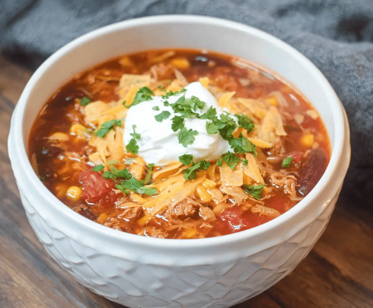 Delicious Instant Pot Loaded Taco Soup topped with shredded cheese, fresh cilantro, and sour cream in a bowl