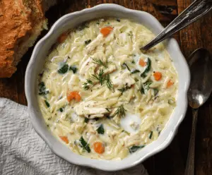 Creamy Chicken Orzo Soup in a bowl garnished with herbs, showcasing tender chicken, orzo pasta, and vegetables in a rich, creamy broth