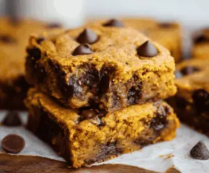 Delicious homemade pumpkin chocolate chip bars with a golden crust topped with melted chocolate chips, perfect for fall desserts and snack cravings.
