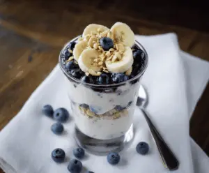 Delicious Blueberry Banana Yogurt Parfait layered with fresh blueberries, sliced bananas, and creamy yogurt in a clear glass.