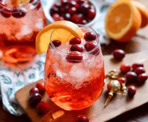 Refreshing Cranberry Aperol Spritz in a glass garnished with fresh cranberries and orange slices