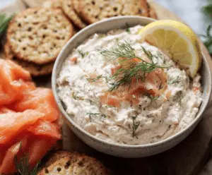Creamy smoked salmon dip garnished with fresh herbs served with crackers.