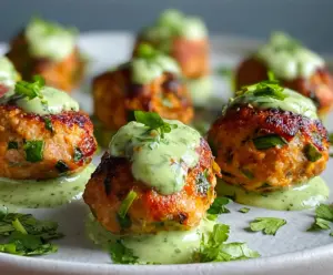 Delicious baked salmon meatballs served with a tangy avocado sauce on a white plate.