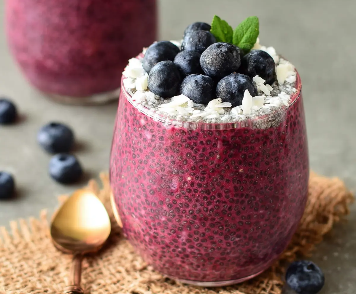 Refreshing berry chia seed pudding served in a glass bowl with fresh berries and a sprig of mint