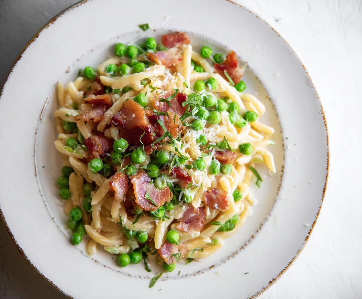 Delicious bacon and fresh peas pasta dish topped with herbs
