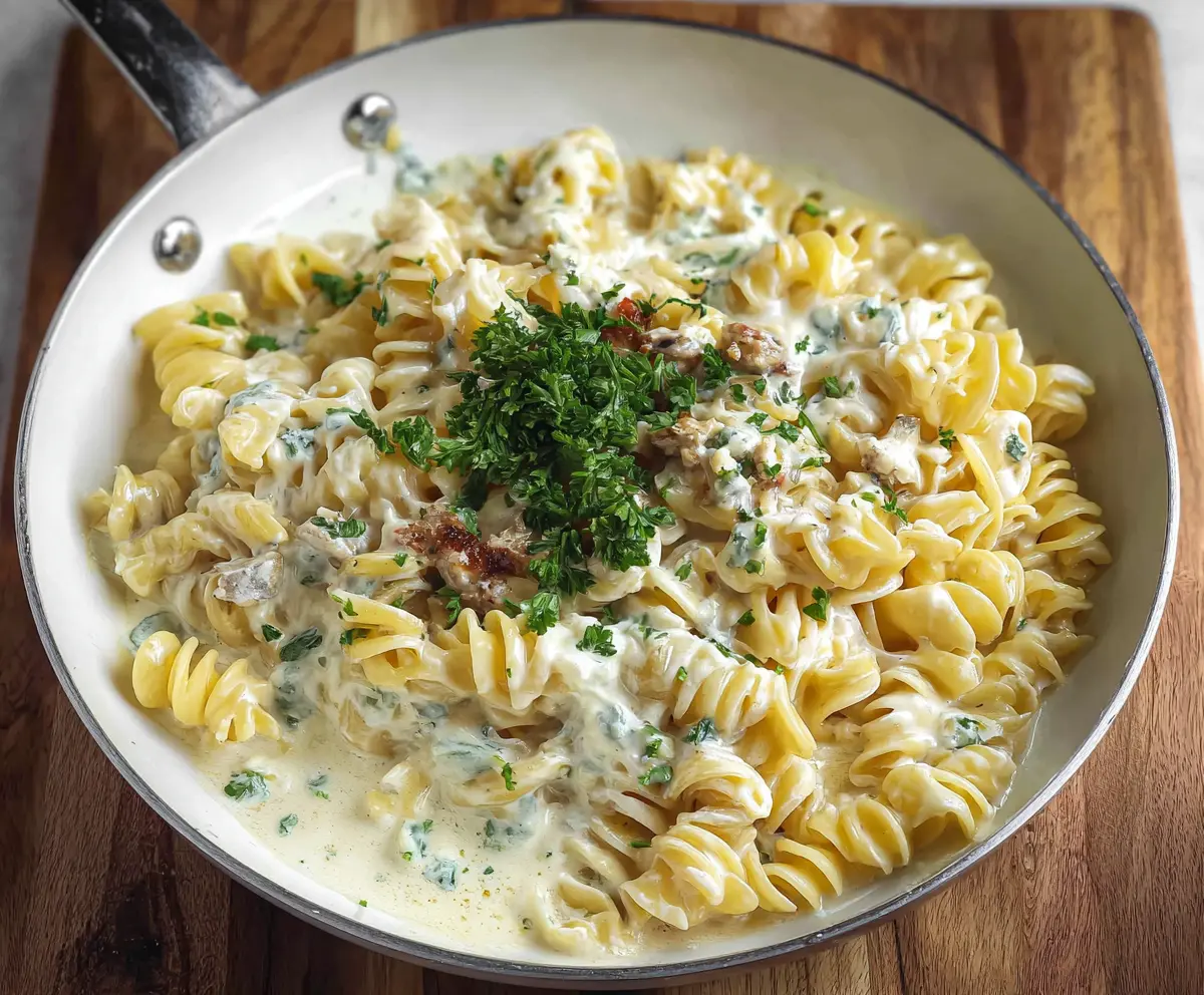 Creamy blue cheese pasta garnished with fresh herbs on a rustic plate.