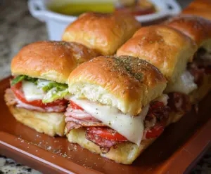 Delicious Hot Italian Sub Sliders with melted cheese, pepperoni, and fresh vegetables on a platter.