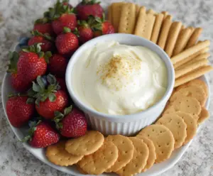 Creamy 3-ingredient cheesecake dip served with fresh fruit on a white plate.