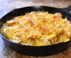 Delicious cheesy potato skillet topped with melted cheese and herbs, perfect for a comfort meal.