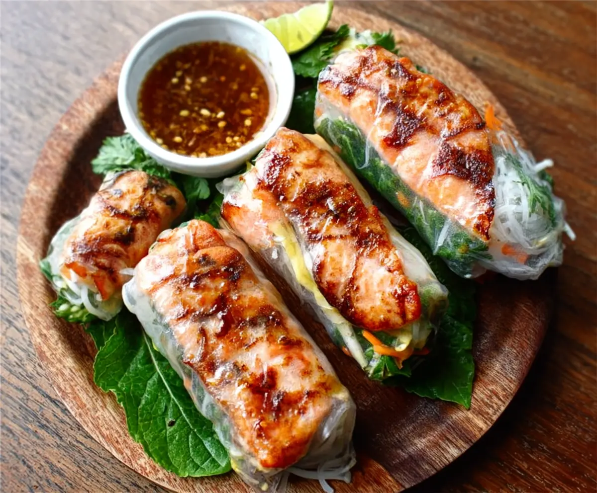 Vietnamese Baked Salmon Spring Rolls with fresh herbs and dipping sauce, served on a white plate.