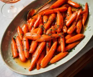 Delicious glazed carrots garnished with fresh herbs on a rustic plate