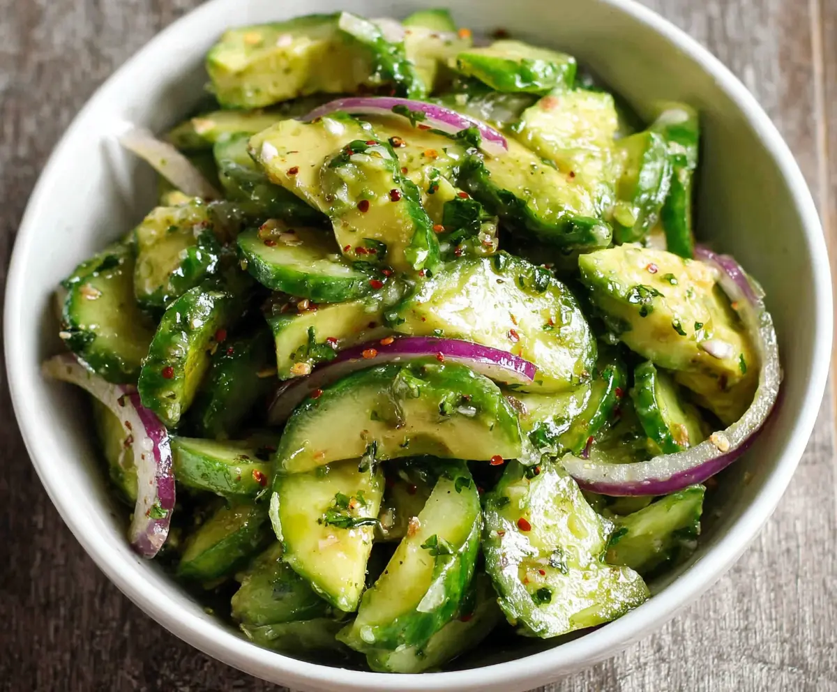 Fresh cucumber and creamy avocado salad garnished with herbs, perfect for a healthy meal.